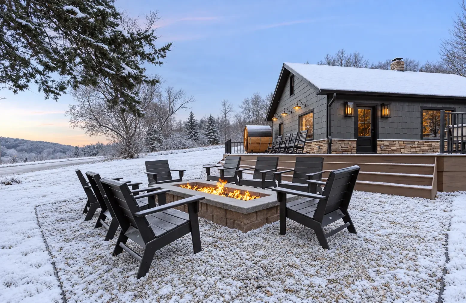 Loess Lakes Ranch rectangular fire pit with black chairs in the snow and the lodge behind it