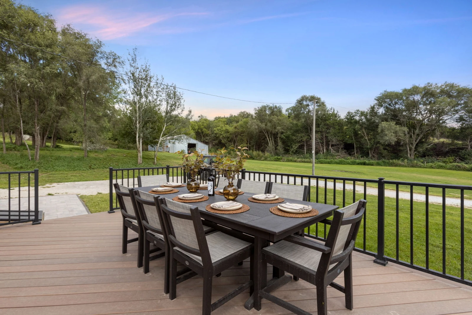 Outdoor dining table set for eight on the ranch deck overlooking the lawn and woodland