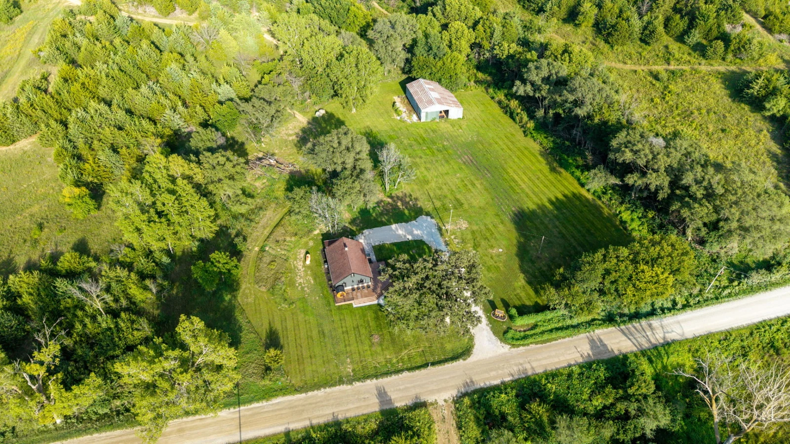 Aerial view of the secluded ranch home, original barn, open lawn and surrounding woodland