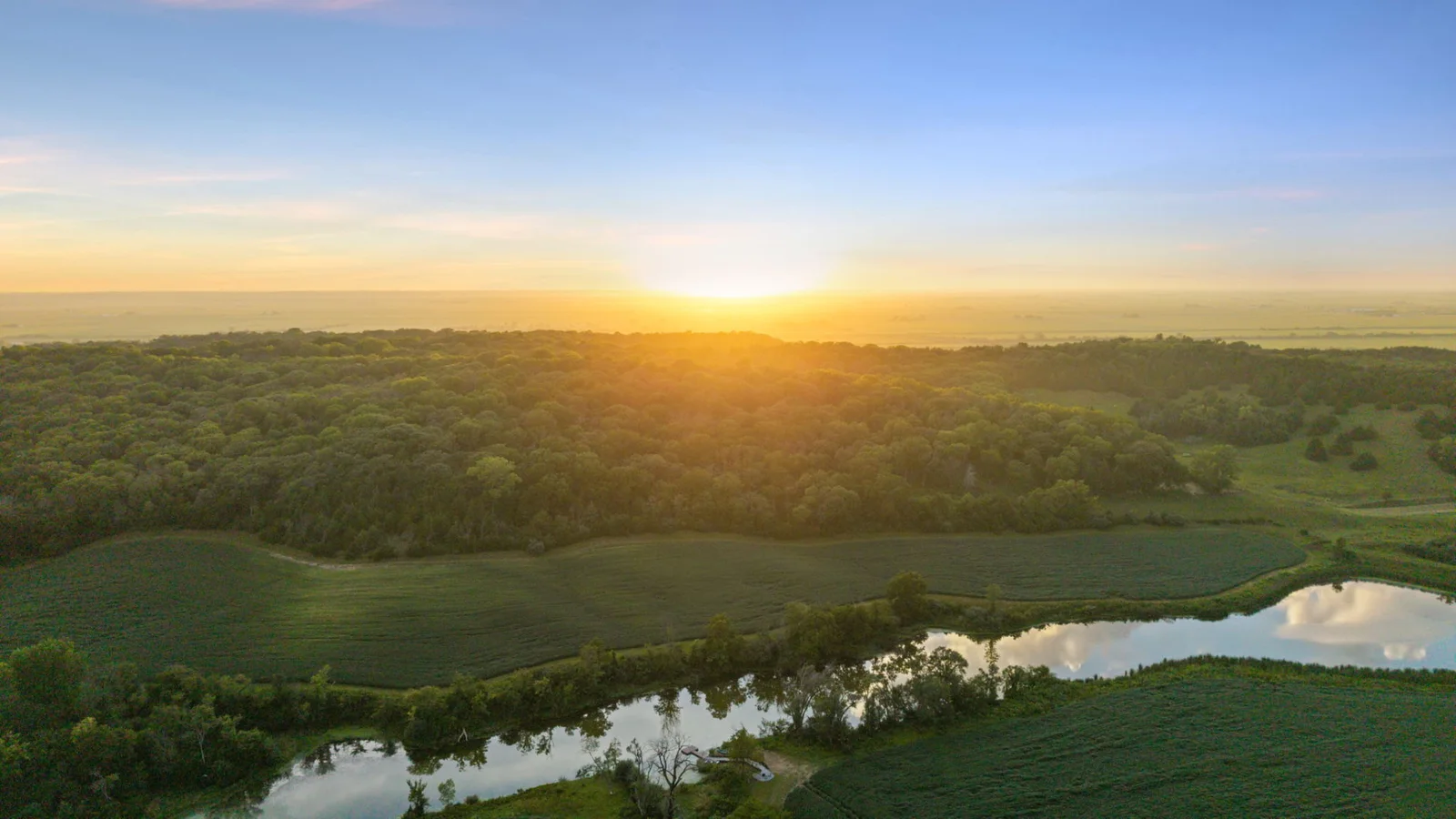 Sunset aerial view across the private lake, wooded ridges and surrounding Loess Hills landscape
